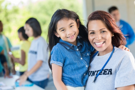 Cheerful volunteer holding an adorable young girl